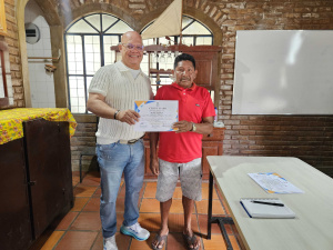 Coordenador do Núcleo de Línguas Estrangeiras da Semed, Jeff Simons, entrega certificado a venezuelano. Foto: Livia Penelope/Ascom Semed