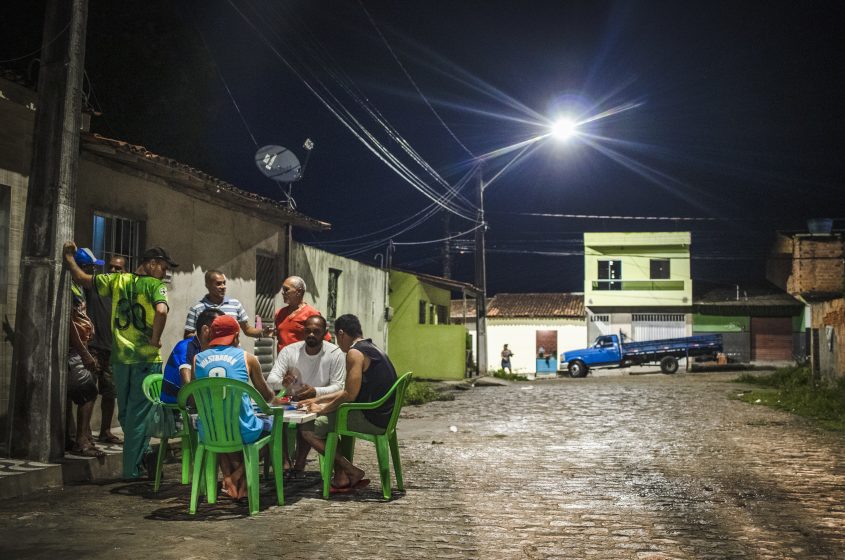 Moradores aproveitam nova iluminação para jogar dominó na porta de casa à noite. Foto: Matheus Alves/Ascom Sima