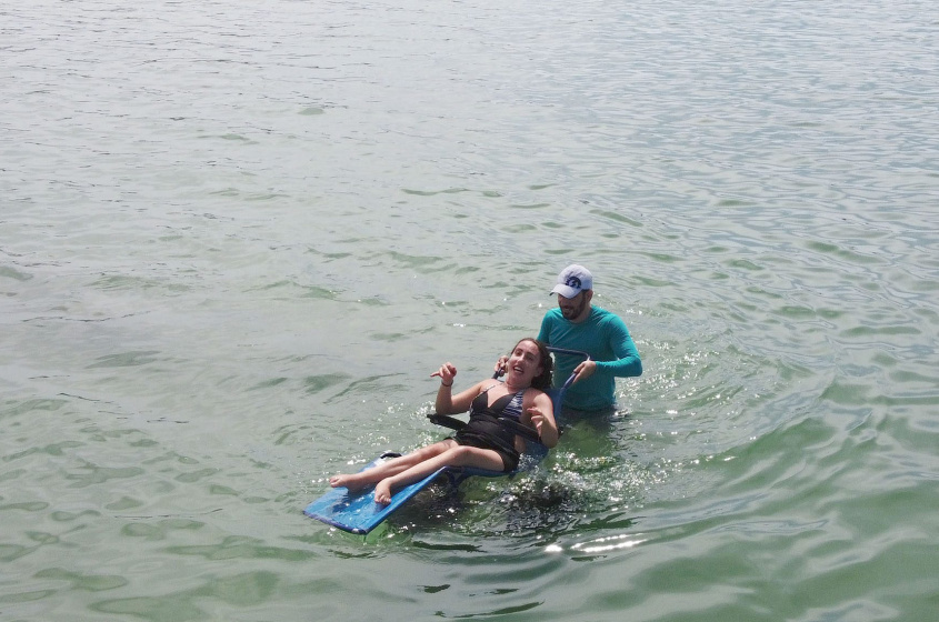 Paula aprovou a experiência de banhar-se no mar da Orla da Praia de Pajuçara com o auxílio de cadeira anfíbia. Foto: Émile Valões / Ascom Semtel
